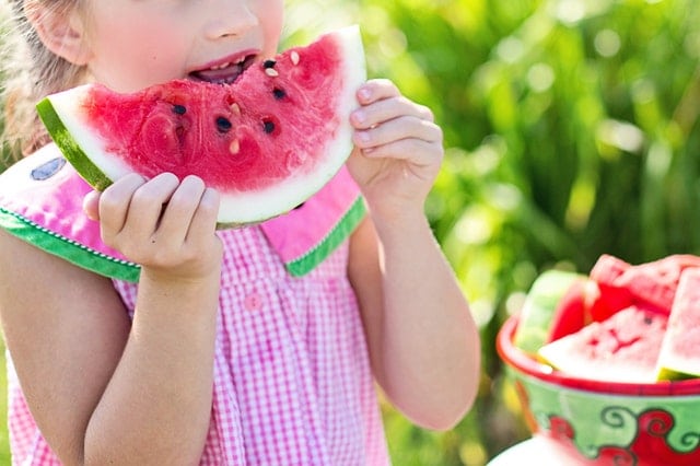 summer and hearing loss child eating a large piece of watermelon