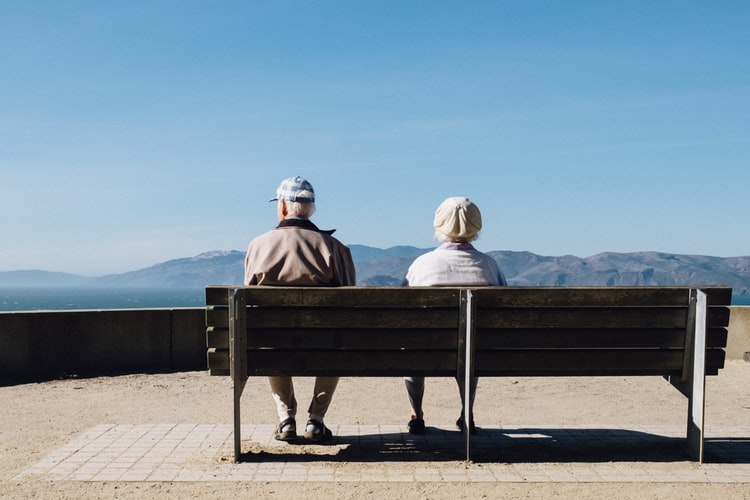 Seniors hearing loss Two seniors sitting on bench overlooking valley