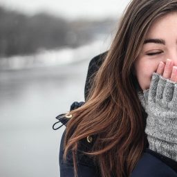 Woman Sneezing into Hand While Outside