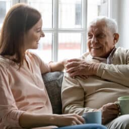 Young adult woman having a conversation on the sofa with her older father.