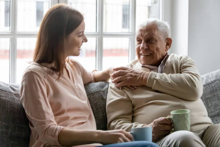 Young adult woman having a conversation on the sofa with her older father.