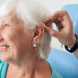 Senior woman smiling as she gets her first hearing aid