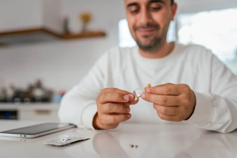 Man examining his hearing aids. Man examining his hearing aids.