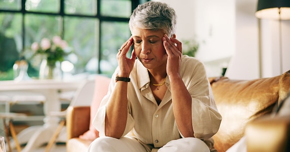 Woman with tinnitus sitting on a couch dealing with the frustrating ringing in her ears. Woman with tinnitus sitting on a couch dealing with the frustrating ringing in her ears.