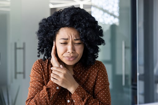Woman experiencing uncomfortable ear pain, or ear stroke. Woman experiencing uncomfortable ear pain, or ear stroke.